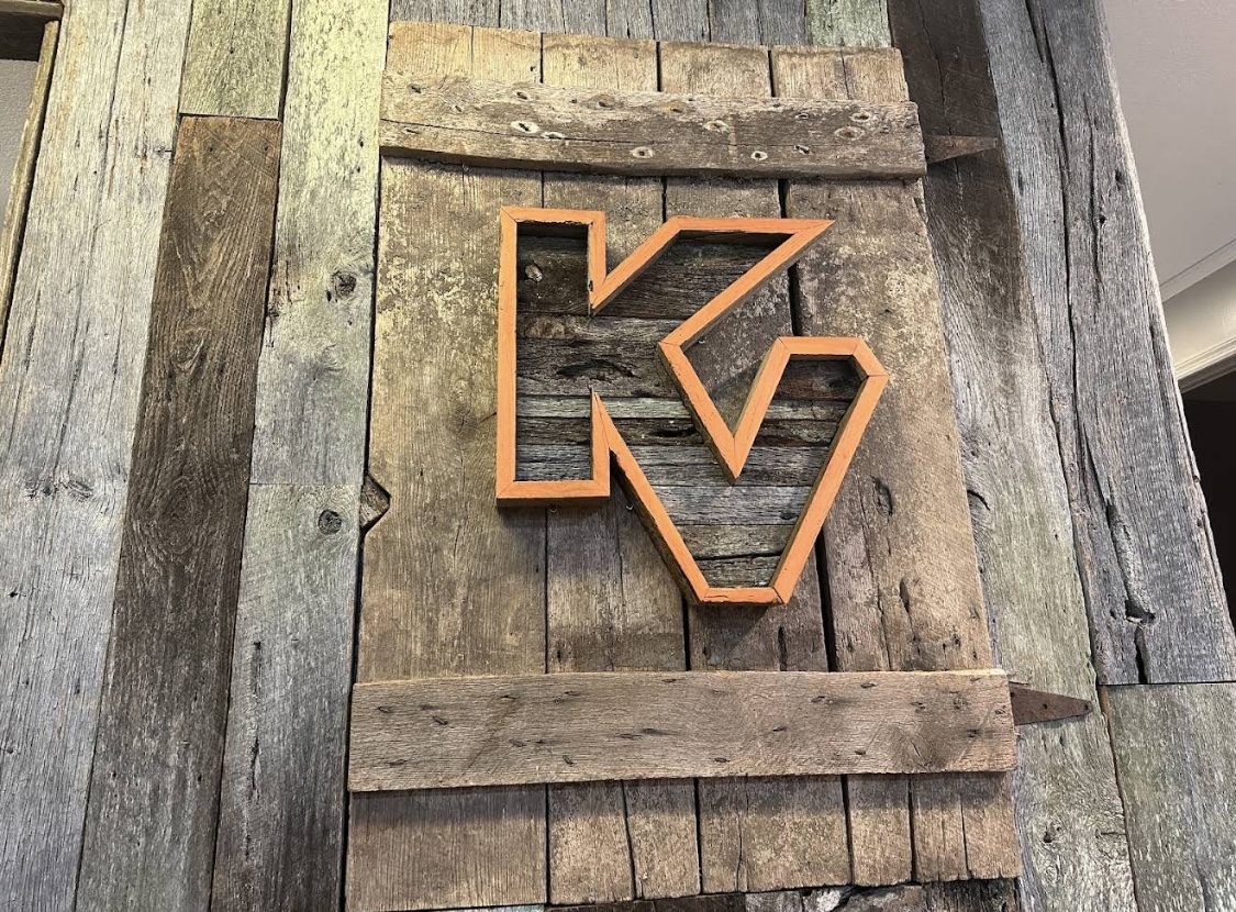 Orange KV letters on a reclaimed barnwood wall